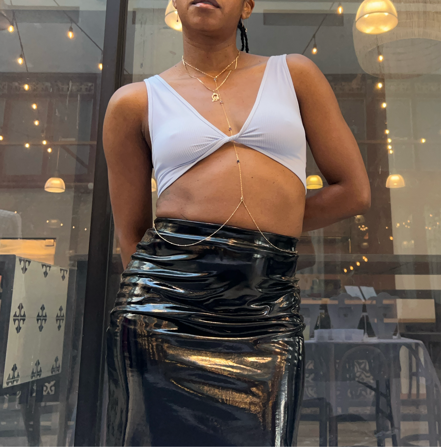 A person wearing a light blue crop top and a black skirt, standing indoors.